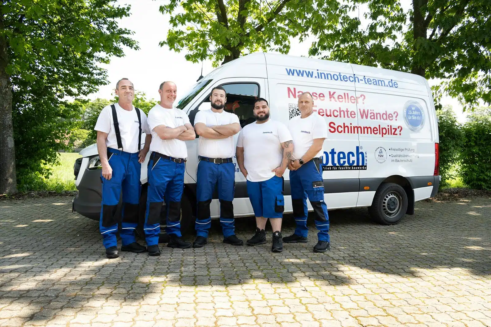 Fünf Handwerker der innotech GmbH in Arbeitskleidung vor dem Firmenfahrzeug